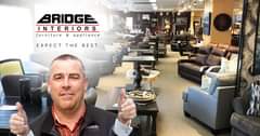 May be an image of 1 person, table, indoor and text that says "BRIDGE INTERIORS furniture & appliance EXPECT THE BEST IOGE"